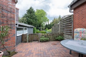A brick patio with a wooden fence, a small shed, and a decorative wall.