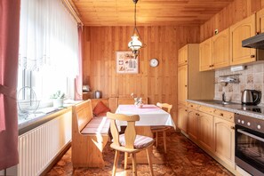 Eine gemütliche Küche mit Holzausbau, einem Esstisch mit Stühlen, einer Bank und einer Pendelleuchte.