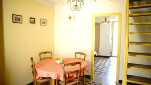 Un espace repas comprenant une table et des chaises, un lustre et un escalier.