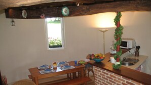 Une cuisine chaleureuse avec une table en bois mise pour deux personnes, un four à micro-ondes et un évier.
