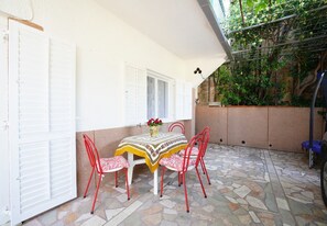 A patio with a table and chairs, a white door, and a stone floor. - Apps Maria: place to spend holidays with friends & family in Split (Croatia) (Podstrana)