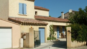 A two-story building with a beige facade, blue shutters, and a tiled roof.