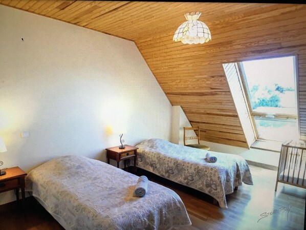 Ein Schlafzimmer mit zwei Betten, einer Holzbalkendecke und einem großen Fenster.