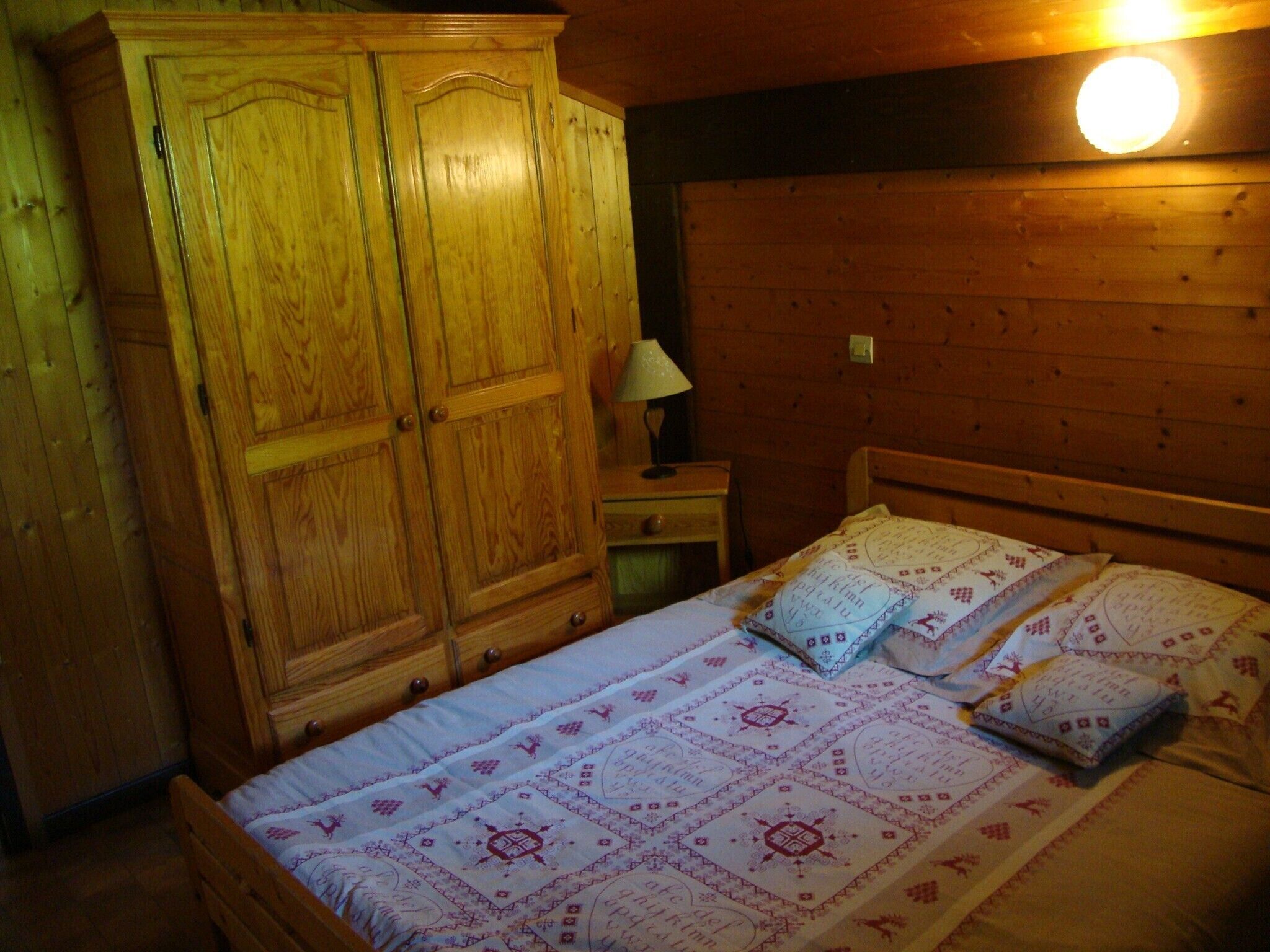 Een houten kamer met een bed, een nachtkastje en een kledingkast.