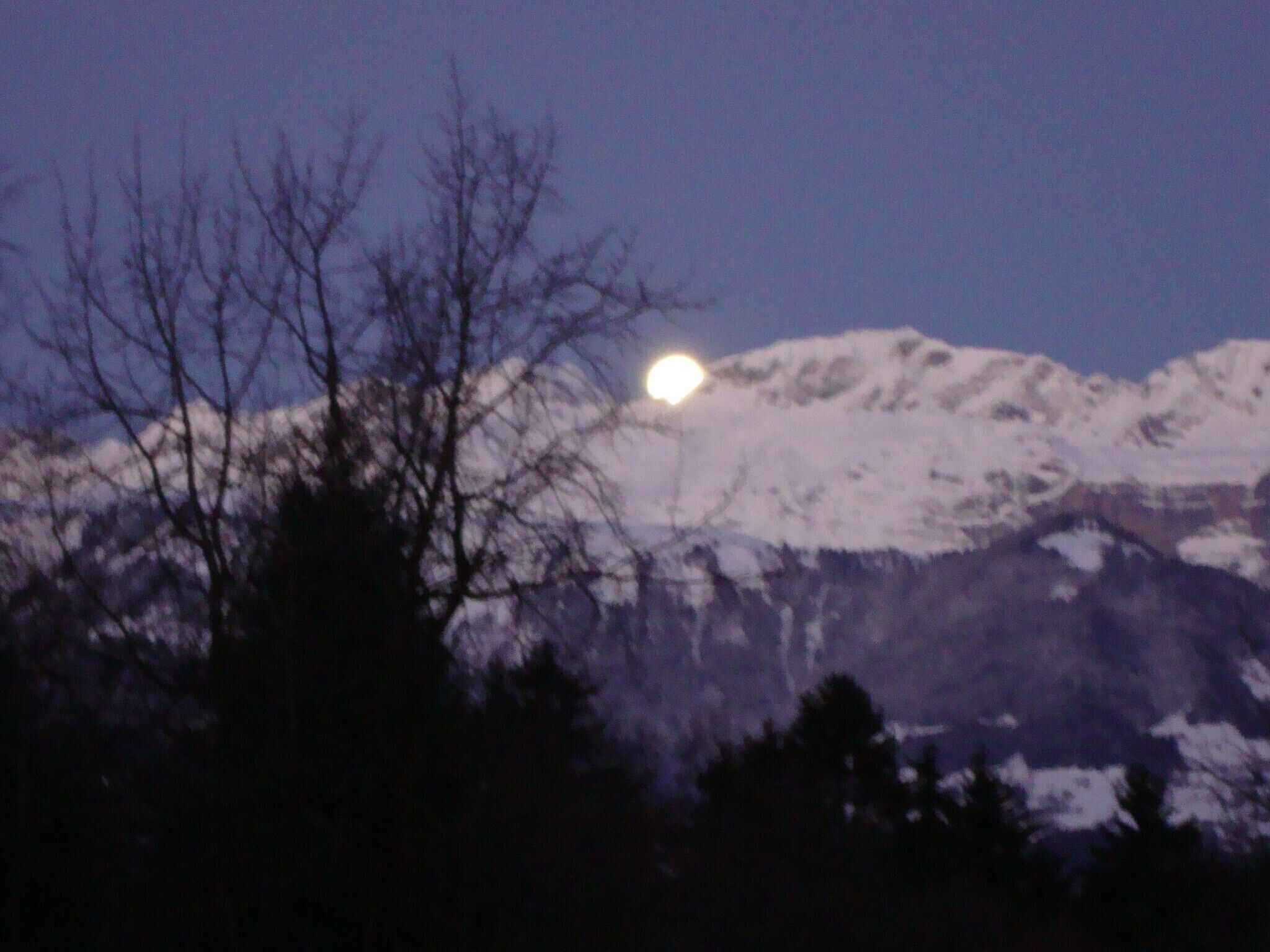 A mountain range with snow-covered peaks under a clear night sky.