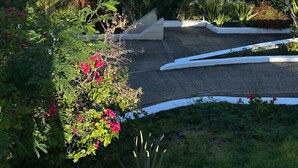 Edifici costaner amb teulada blanca, envoltat de vegetació exuberant i vista al mar.