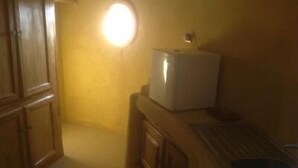 A narrow hallway with wooden cabinets and a white refrigerator. - Between sea and lagoon "KEUR OCEAN" A PARADISE (Nianing)