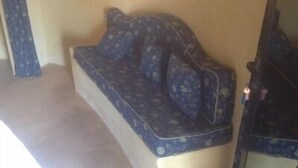A room with a patterned sofa against a wall, a small table with keys, and a carpeted floor. - Between sea and lagoon "KEUR OCEAN" A PARADISE (Nianing)