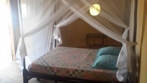 A single bed with a canopy, a small table, and a wall-mounted shelf. - Between sea and lagoon "KEUR OCEAN" A PARADISE (Nianing)
