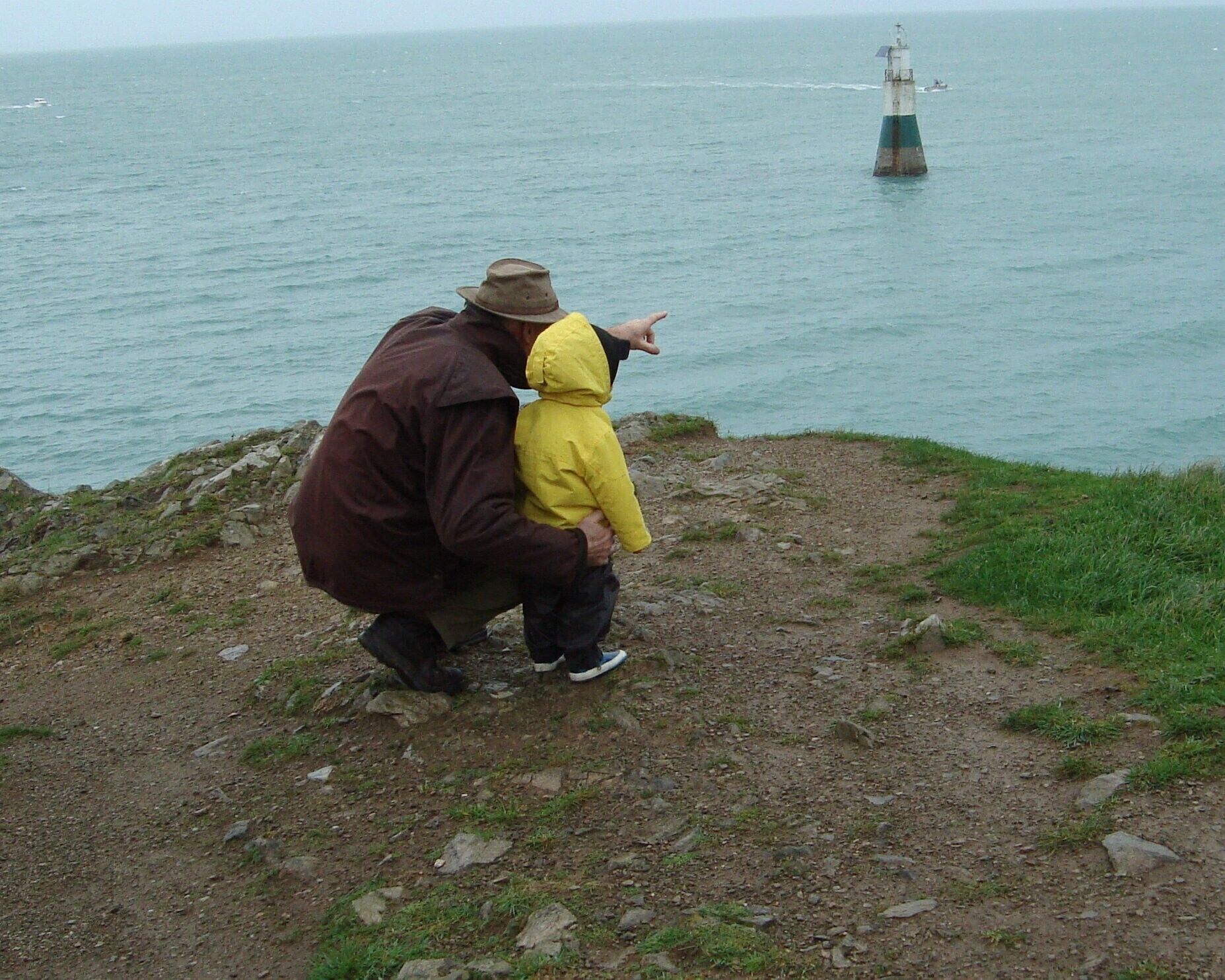 A rocky shoreline with a lighthouse in the distance.