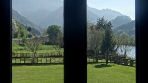 A view through a window with a mountain landscape, including a bridge and a body of water.