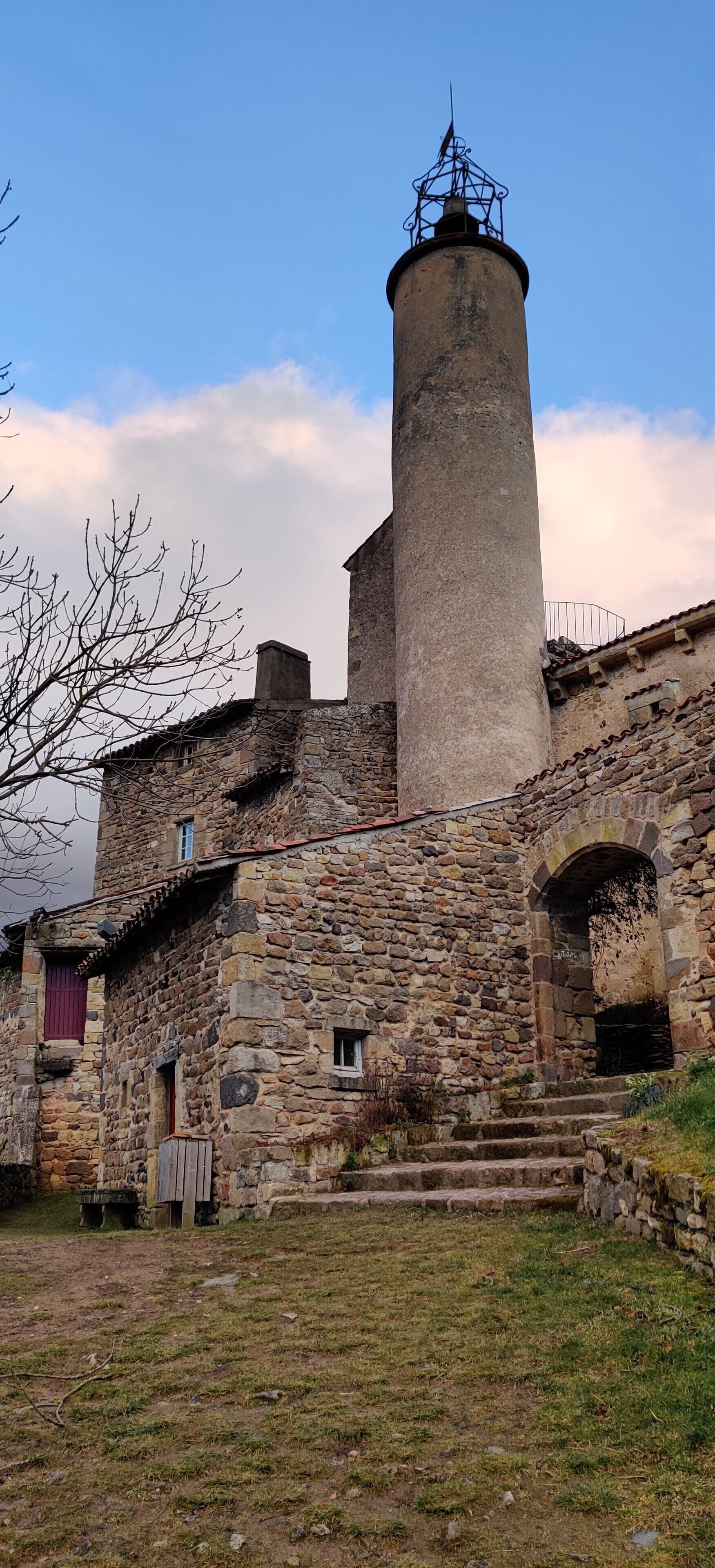 Un edificio de piedra con una torre cilíndrica y un balcón.