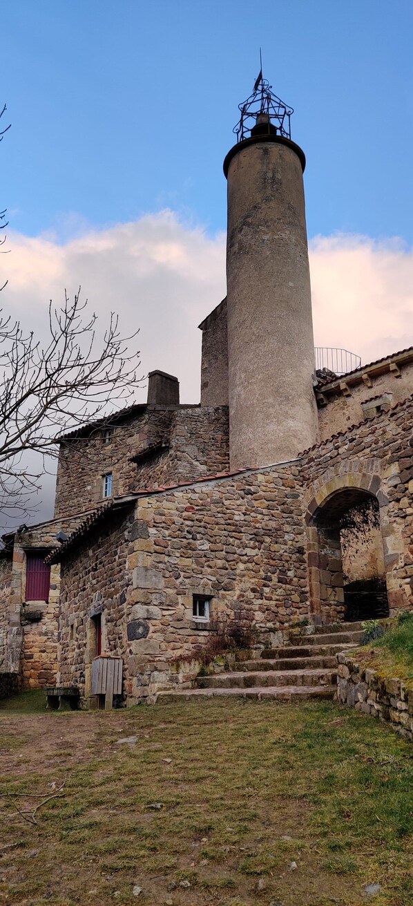 Un edificio de piedra con una torre cilíndrica y un balcón.
