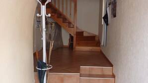 Una escalera que conduce a un piso de madera con una pared de azulejos y un perchero.