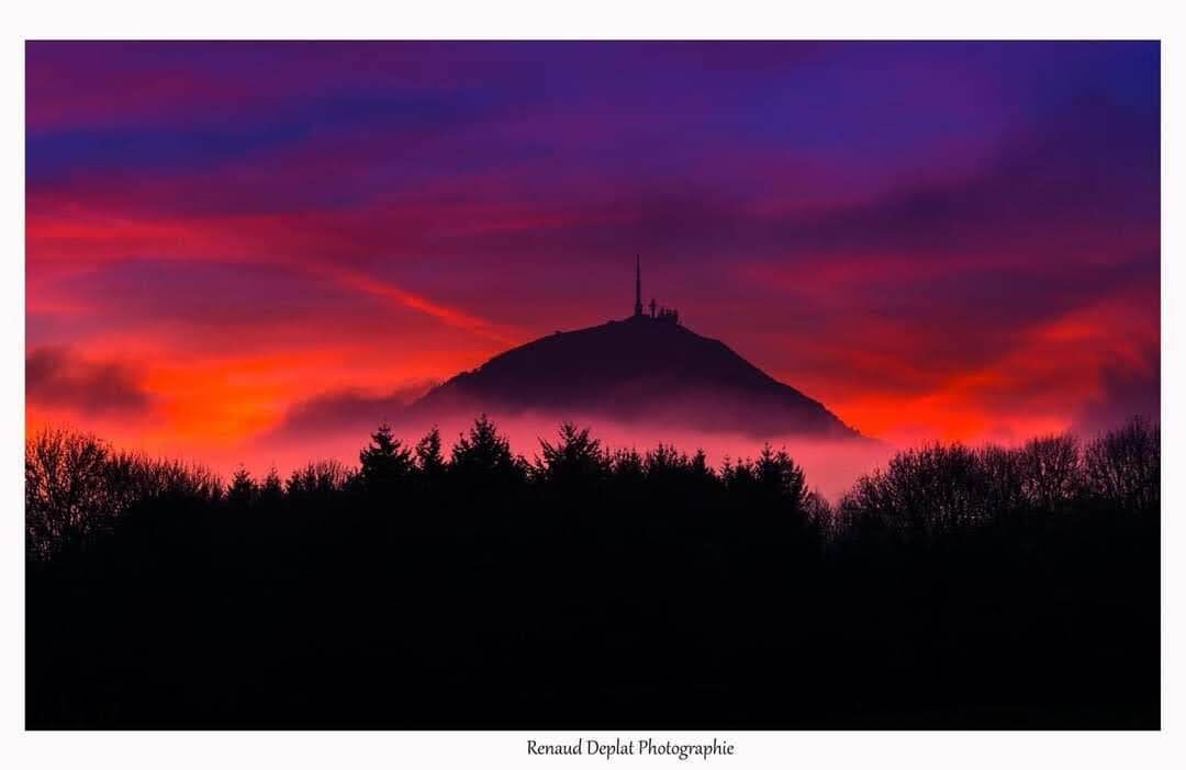 Een berg met de silhouet van een radiozendmast voor een levendige zonsondergang.