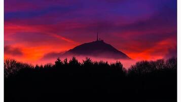 Een berg met de silhouet van een radiozendmast voor een levendige zonsondergang.