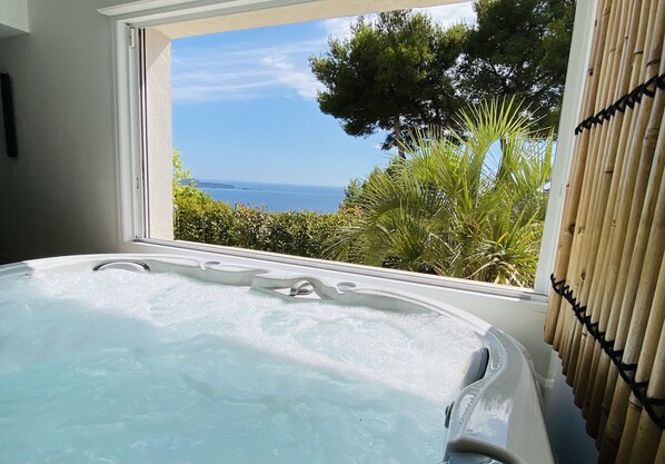 A hot tub with a view of the sea and greenery.