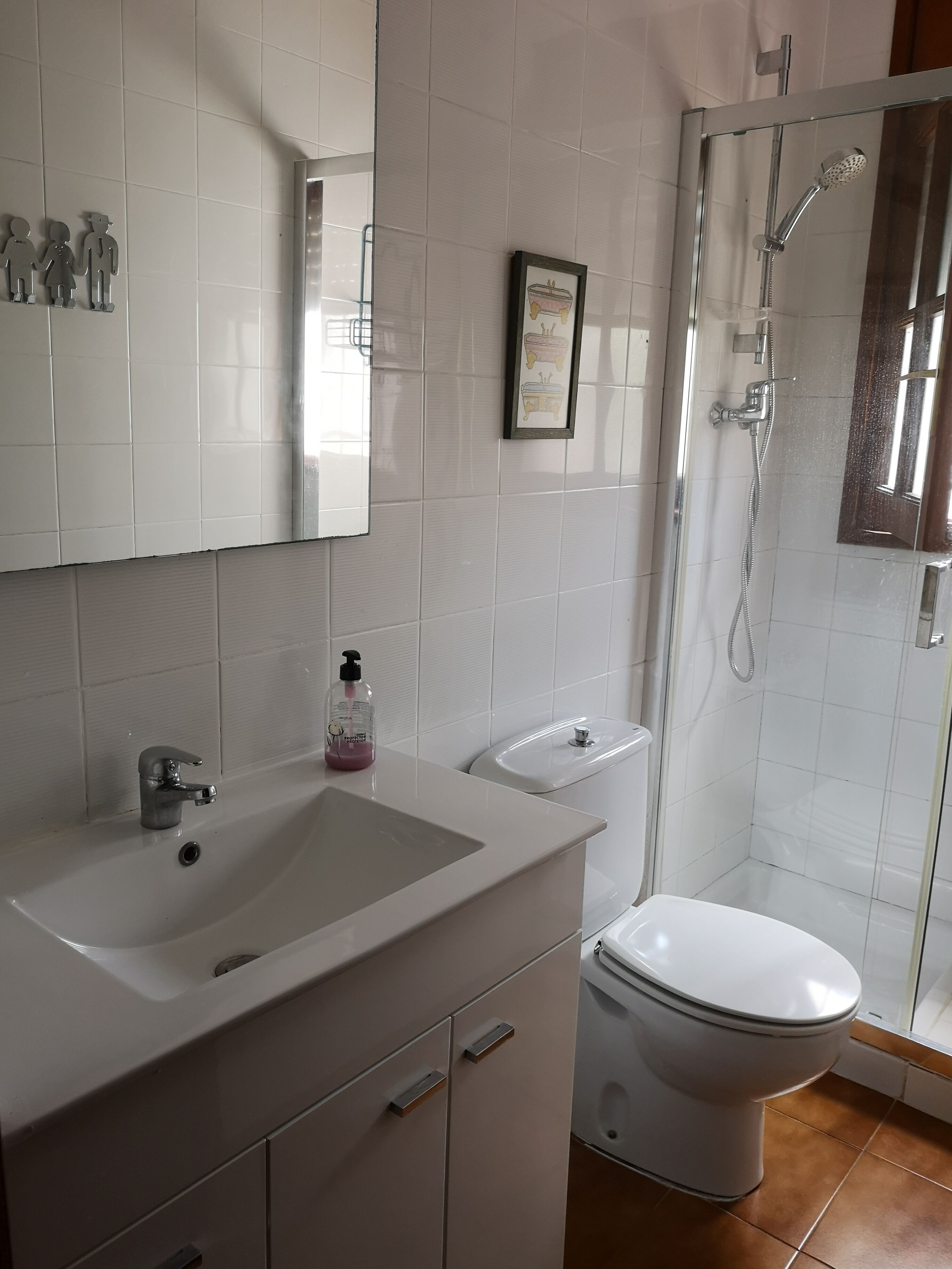 Une salle de bain avec un lavabo blanc, des toilettes et une douche à parois de verre.