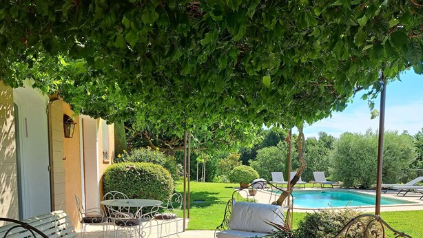A patio with metal furniture, a table, and a view of a swimming pool.