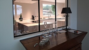 A modern kitchen with a large mirror reflecting the interior, a wooden countertop, and a black lamp.