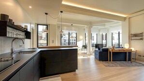A modern kitchen with a central island, built-in appliances, and a large window offering a city view. - Allegra by FeelFree Rentals (Donostia)
