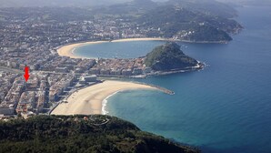 An aerial view of a coastal city with a prominent beach, a small island, and a dense urban area with buildings. - Allegra by FeelFree Rentals (Donostia)