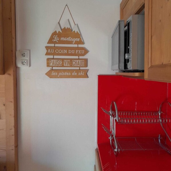 A kitchen with a red countertop, a metal rack, and a wall-mounted sign with French text. - apartment/ flat - VAL THORENS (Les Belleville)