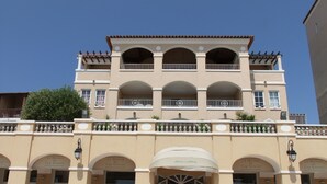 A multi-story hotel with a symmetrical facade, featuring arched balconies and a central entrance with a canopy.