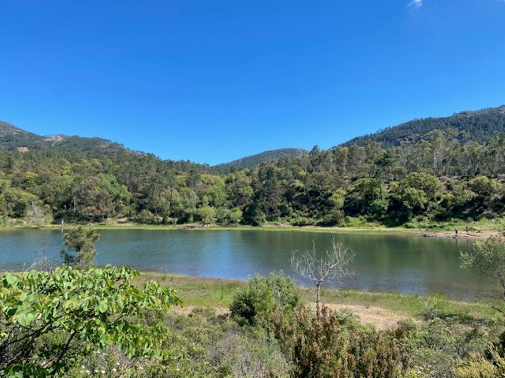 Paisagem natural com um lago, rodeado por colinas e vegetação densa.