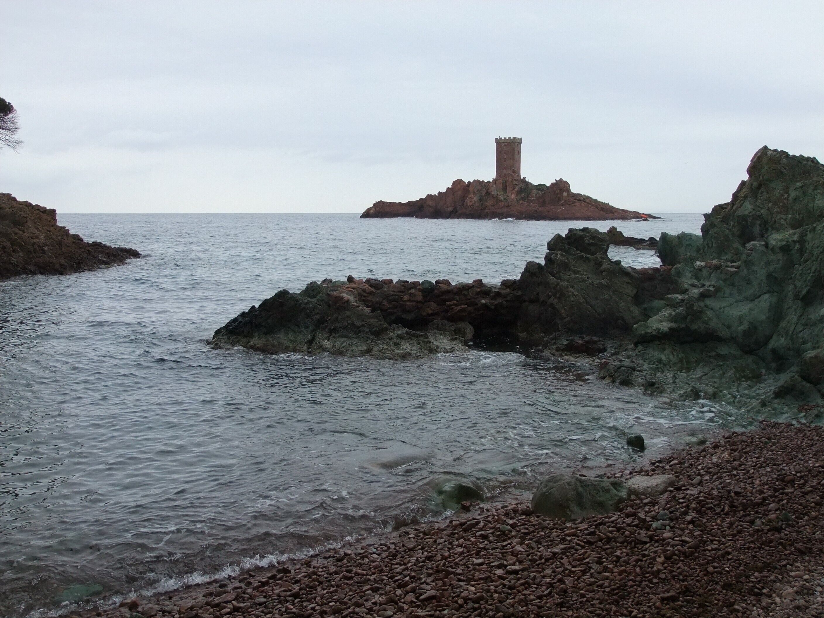 A coastal landscape with rocky terrain and a tower on a small island.