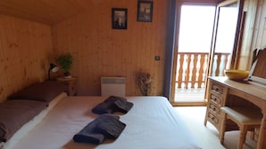 A wooden cabin room with a bed, a desk, and a balcony. - Beautiful Chalet for 8 people, 4 bedrooms, 3 bathrooms and beautiful views (Thollon-Les-Mémises)