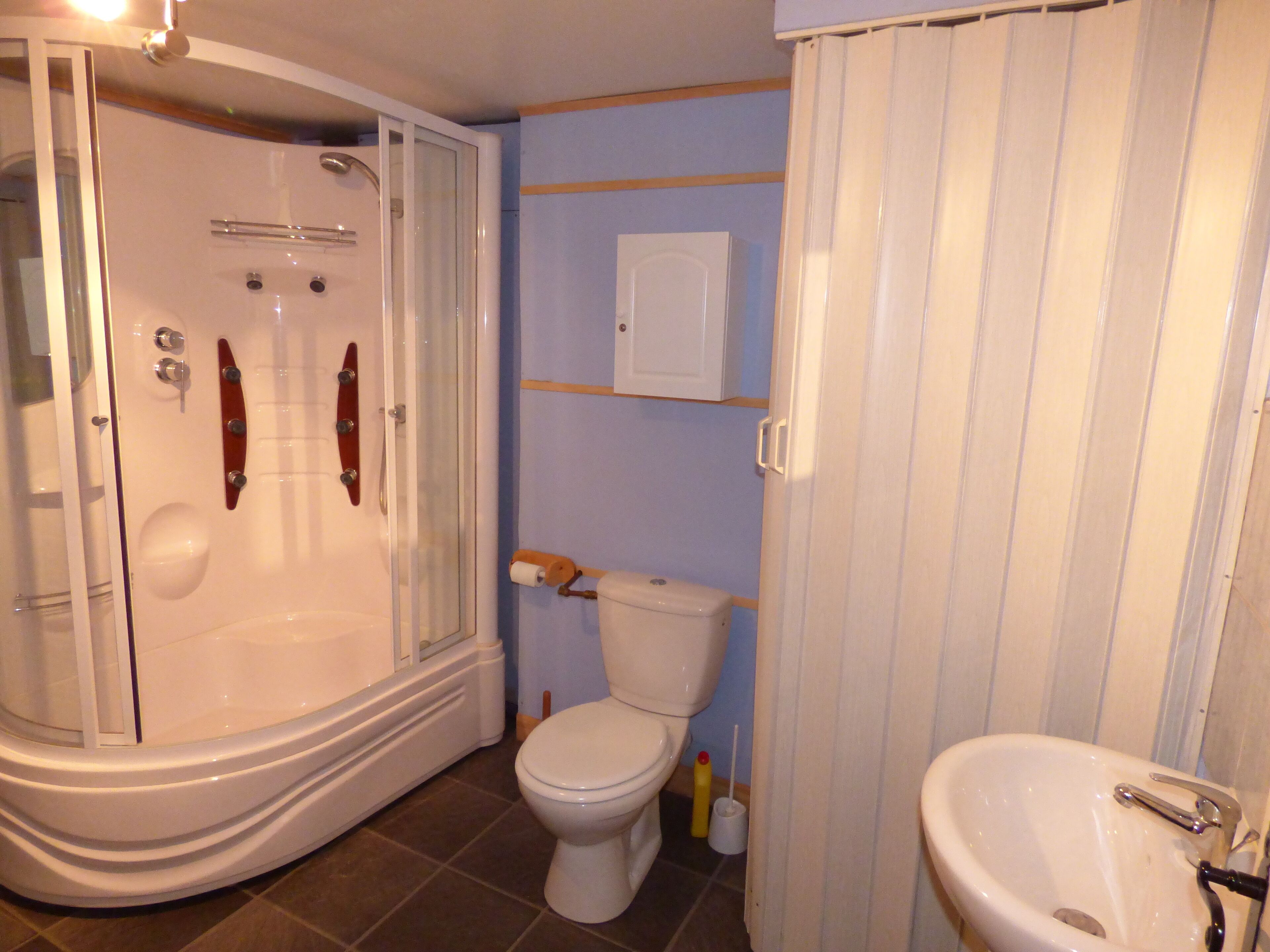 A bathroom with a glass-enclosed shower, a toilet, and a sink.