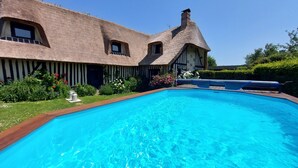 A large swimming pool with a thatched-roof building in the background. - In the estuary of the Seine, a few minutes away from Honfleur, a real Longere (Eure)