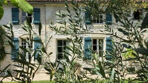 Un bâtiment en pierre avec des volets bleus et un jardin à l’avant.