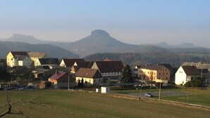 Een landelijk dorp met traditionele huizen, een heldere lucht en een berg op de achtergrond.