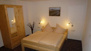 Een slaapkamer met een houten bed, twee bedlampen, een spiegel en een aan de muur bevestigd schilderij.