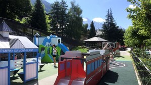 Un parque infantil con un tobogán rojo y estructuras de juego.
