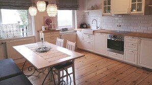 Uma cozinha com armários brancos, bancada de madeira e um espaço de refeições com mesa e cadeiras.