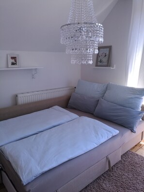 Un dormitorio con cama, candelabro, radiador y un cuadro en la pared.