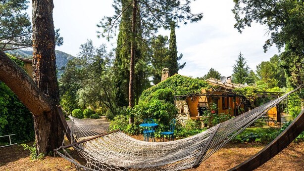 A hammock in a garden with a stone building and trees in the background. - house / villa - 8 rooms - 8/10 persons (Auriol)