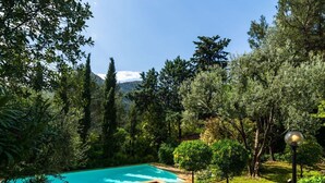 A swimming pool surrounded by lush greenery and trees, with a stone pathway leading to it. - house / villa - 8 rooms - 8/10 persons (Auriol)