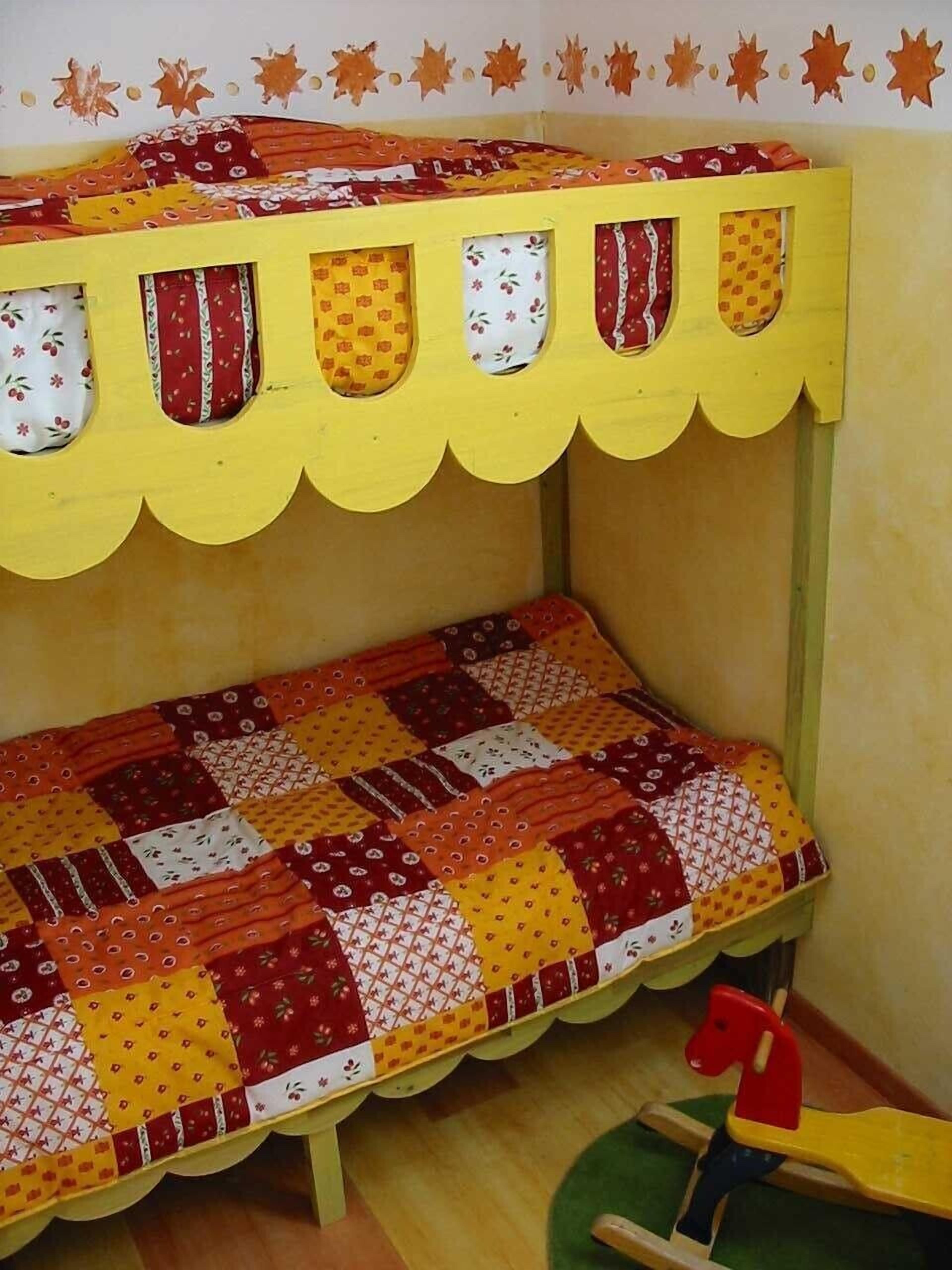 Una cama litera infantil con colcha de retazos, un caballito de juguete y una pared decorada con estrellas.