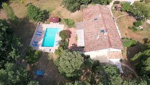 Une vue aérienne d’une maison avec une piscine, entourée d’arbres et d’un jardin.