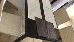 Ein Essbereich mit einem schwarzen Tisch und Stühlen mit gewobenen Sitzflächen.