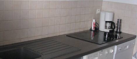 A compact kitchen with a built-in dishwasher, a coffee maker, and a microwave.