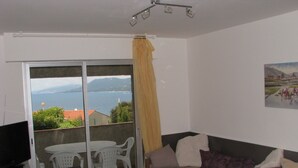 Ein Balkon mit Tisch, Stühlen, einer Couch und einem Fernseher.