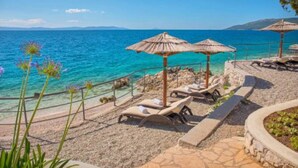 A beachside resort with sun loungers, thatched umbrellas, and clear blue waters. - Modern Villa w / pool, a few minutes from the sea, surrounded by nature (Brgod)