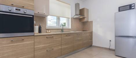 A modern kitchen with a built-in oven, a stainless steel refrigerator, and wooden cabinets.