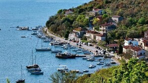 A coastal village with boats docked along the shore and houses built on a hillside. - Modern Villa w / pool, a few minutes from the sea, surrounded by nature (Brgod)