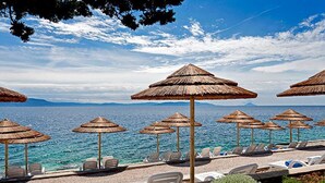 A beach with thatched umbrellas and lounge chairs facing the sea. - Modern Villa w / pool, a few minutes from the sea, surrounded by nature (Brgod)